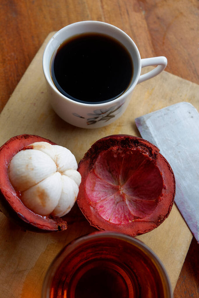 The photo is a photo of a person holding mangosteen and tea - Photo, Image