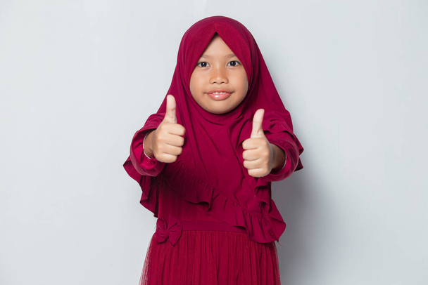 Ασιατικό μουσουλμανικό κοριτσάκι φορώντας χιτζάμπ με εντάξει σημάδι χειρονομία tumb up - Φωτογραφία, εικόνα