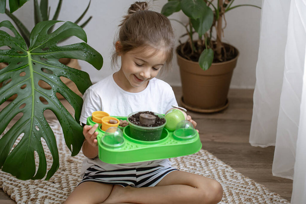 Ein kleines Mädchen mit einem Baby-Set für den Eigenanbau einer Pflanze. - Foto, Bild