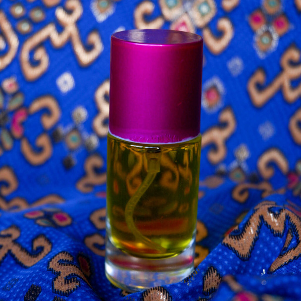 parfum fles met een gele parfum kleur op een blauwe batik achtergrond - Foto, afbeelding