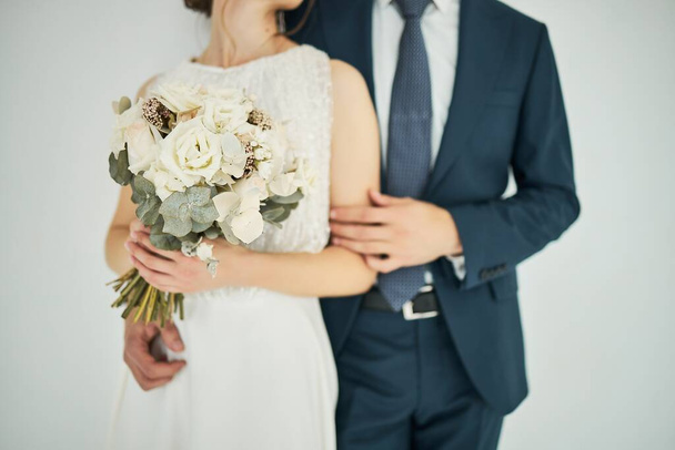 bride holding a bouquet of flowers in her hand, the groom embracing her - Photo, image