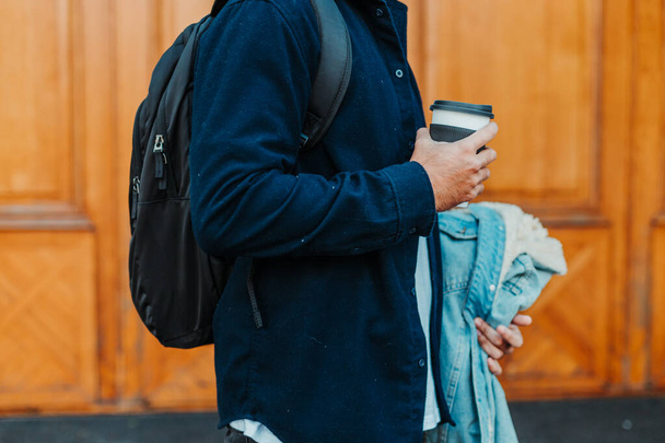 A side view of a stylish male in a blue shirt holding a cup of coffee - Photo, Image