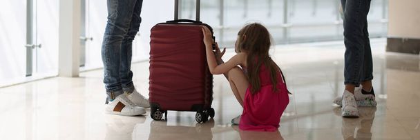 Hombre y mujer de pie a distancia el uno del otro en medio de un niño con una maleta - Foto, Imagen