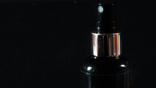 A closeup of a black spray bottle on dark background - Foto, afbeelding