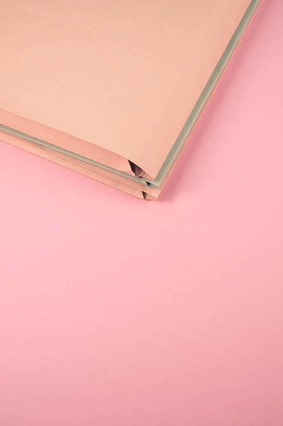 A vertical shot of paper files on a pink surface - Фото, изображение