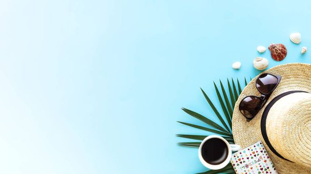 Travel, vacation concept. Hat with different sea shells, green palm leaf, passport, eyeglasses and cup of coffee on blue sky background. Travelling to warm countries. Banner with copy space for text - Foto, immagini
