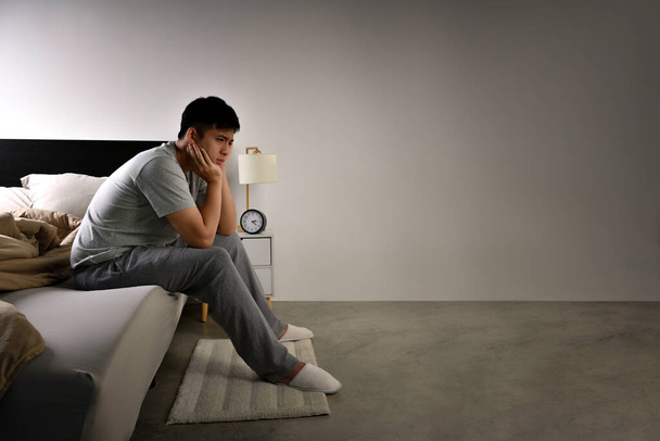 Deprimido jovem asiático sentado na cama não pode dormir de insônia - Foto, Imagem