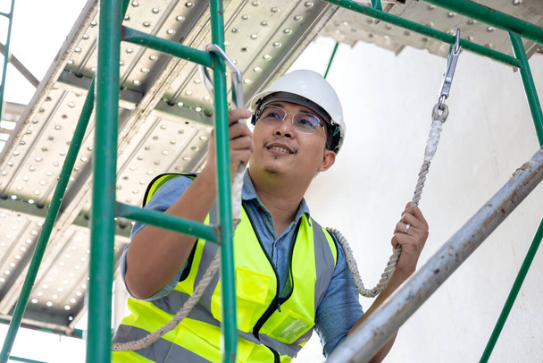 Pendant les travaux en hauteur, un travailleur de la construction porte une ceinture de sécurité. sur un fond de plate-forme de forage pour une plate-forme structurelle - Photo, image
