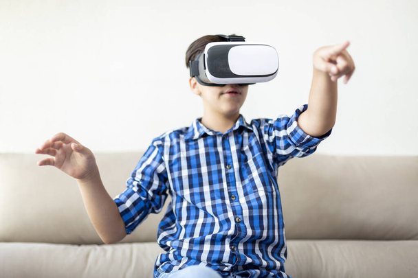 Teenager mit VR-Brille, der die Arme bewegt und gestikuliert. Konzept der neuen Technologien zu Hause. - Foto, Bild