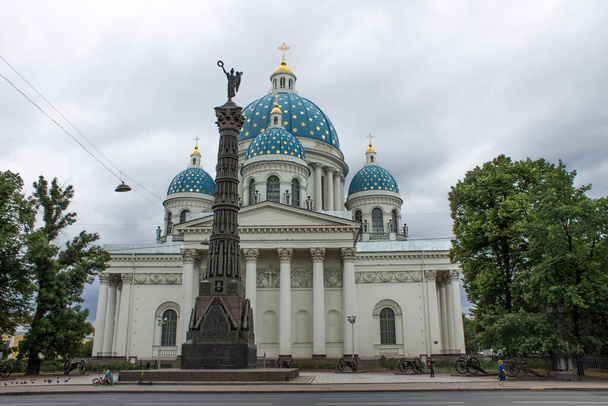 Saint PETERSBURG, RUSSIA-July, 20, 2021: the facade of the Izmailovsky Cathedral with blue domes and a column against the background of a cloudy sky and green trees at summer day - Zdjęcie, obraz