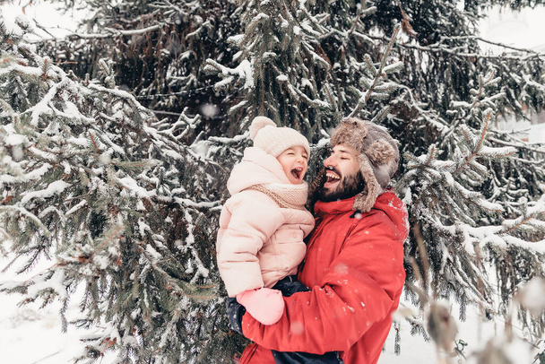 Handsome bearded young dad and his little cute daughter are having fun outdoor in winter. Enjoying spending time together. Family concept - Fotoğraf, Görsel