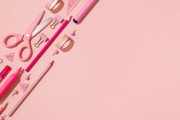 Top view photo of ordered pink stationery composition adhesive tapes ruler pins binder clips scissors pencils felt pens on isolated pastel pink background with empty space - 写真・画像