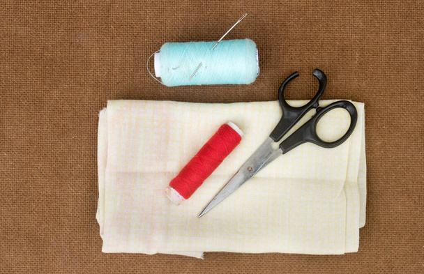 Группа швейных инструментов и предметов для вязания и ткачества, размещенных на бумажной доске коричневого цвета. DIY Искусство и ремесло. - Фото, изображение