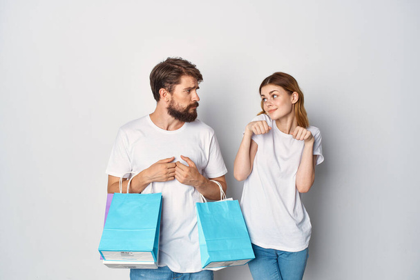 pareja joven asesinada en camisetas con paquetes en sus manos estilo de vida compras - Foto, Imagen