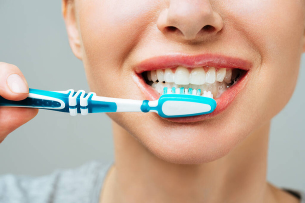 Nainen, jolla on terveet valkoiset hampaat, pitää hammasharjaa ja hymyilee. Suullinen, hygienia käsite - Valokuva, kuva