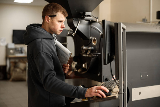 Joven trabajador especialista está asando café en hangar - Foto, Imagen