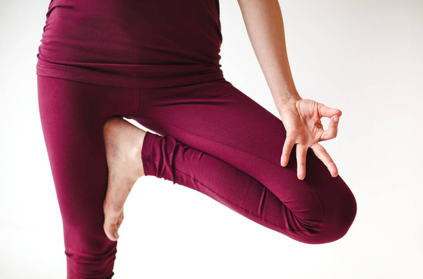 Unerkennbare Frau in Sportbekleidung sitzt mit überkreuzten Beinen und mudra Händen auf Matte und macht Yoga, während sie Achtsamkeit übt - Foto, Bild