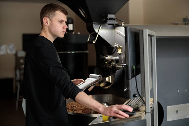 Fiatal szakmunkás kávét süt a hangárban. - Fotó, kép
