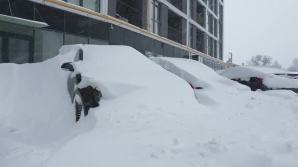 Αυτοκίνητα που καλύπτονται από χιόνι μετά από χιονοθύελλα. Κατοικίες κτίριο στο παρασκήνιο. - Πλάνα, βίντεο