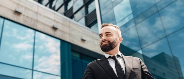 Portrait d'un homme mûr riche en costume regardant l'espace de copie, homme d'affaires heureux posant sur un immeuble de bureaux en verre - Photo, image
