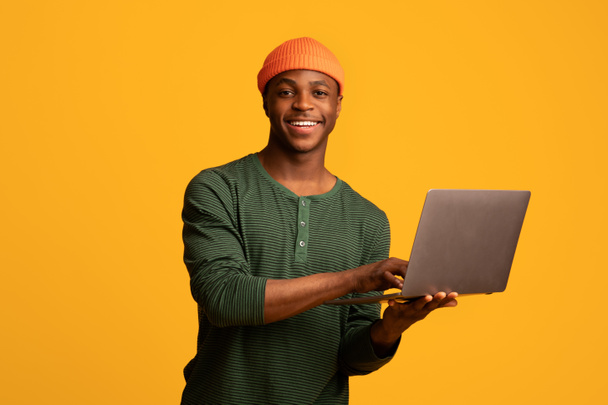 Retrato de un joven afroamericano feliz con computadora portátil - Foto, imagen