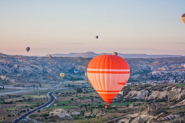 Hőlégballonok repülnek a völgy felett Cappadociában, Törökországban. Goreme Léggömb Fesztivál. Gyönyörű hőlégballonok szállnak fel napkeltekor. Hőlégballonok a kék égen - Fotó, kép