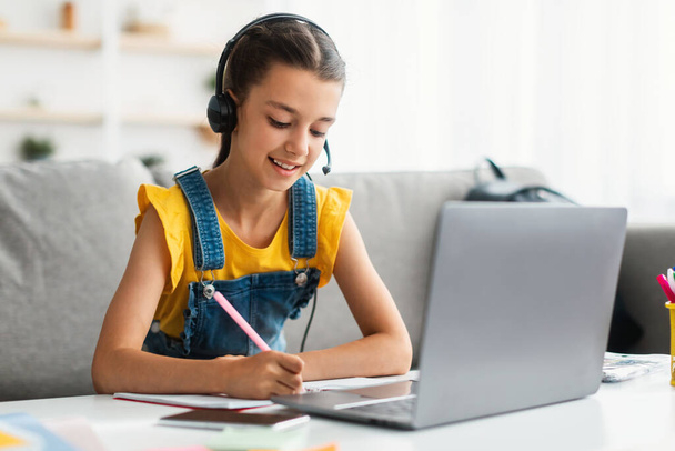 Dziewczyna korzystająca z laptopa, wideorozmowa z nauczycielem, pisanie w notatniku - Zdjęcie, obraz