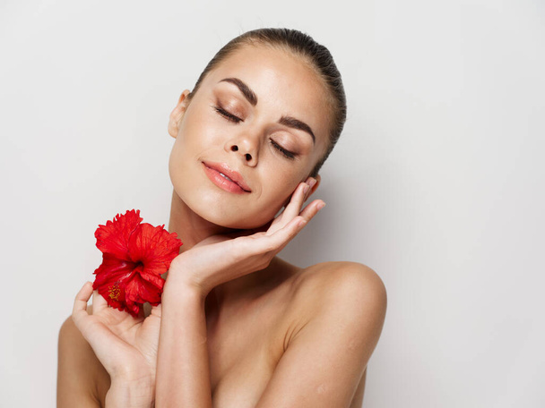 mulher com ombros nus e cosméticos flor vermelha charme pele pura - Foto, Imagem