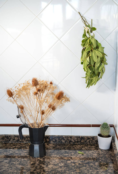 Background of a coffee maker used as a vase and laurel drying on the wall. Kitchen with floral decoration with copy space. - Photo, Image