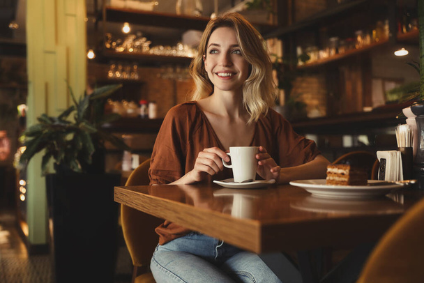Young woman with cup of coffee at cafe in morning - Foto, Imagen