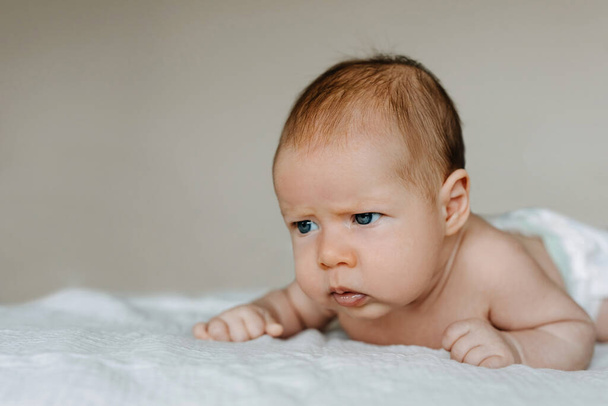 Два місяці дитина тримає голову, з серйозним виразом обличчя, намагаючись повзати
. - Фото, зображення
