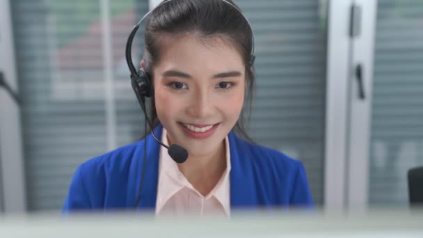 Vezetékes fülhallgatót viselő üzletasszony aktívan dolgozik az irodában - Felvétel, videó