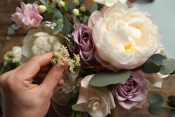 Florist creating beautiful bouquet at table, top view - Fotó, kép