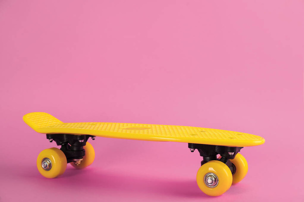 Yellow skateboard on pink background. Space for text - Foto, Imagem