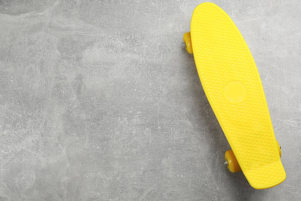 Yellow skateboard on grey stone background, top view. Space for text - Photo, Image