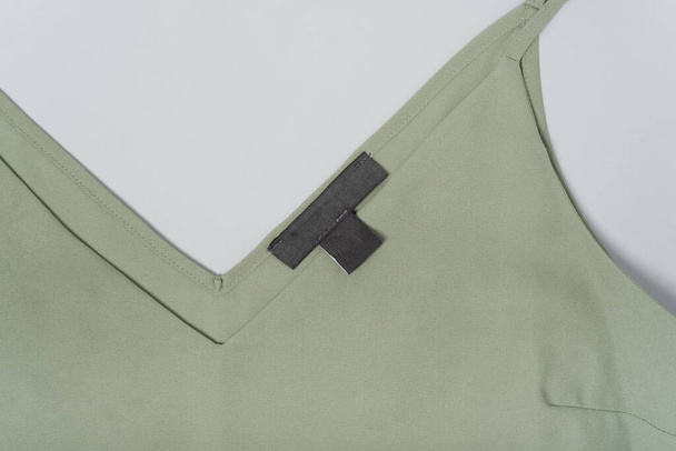 Макет черный пустой этикетки на зеленой блузке цвета хаки крупным планом. - Фото, изображение