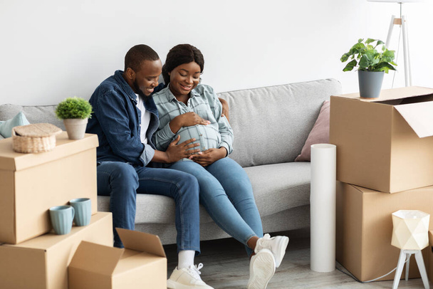 Счастливые молодые чернокожие супруги с беременной женой переезжают в новую квартиру - Фото, изображение