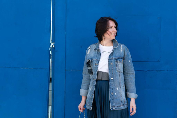 молодая красивая женщина позирует в синей джинсовой куртке снаружи - Фото, изображение