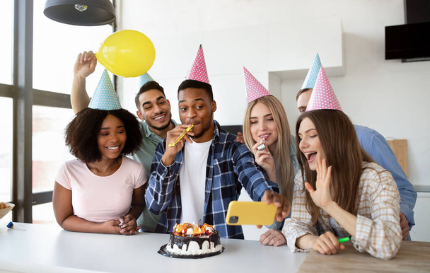 Amigos multiétnicos alegres tomando selfie durante a celebração de aniversário com delicioso bolo em casa - Foto, Imagem