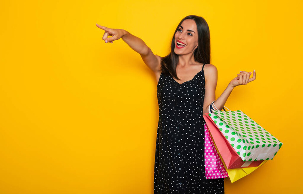 Beautiful happy young stylish brunette woman in a dress is posing with many colorful shopping bags and having fun - Foto, Imagen