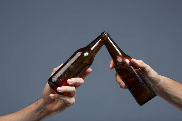 Two friends clinging bottles in the dark gray background - Photo, image