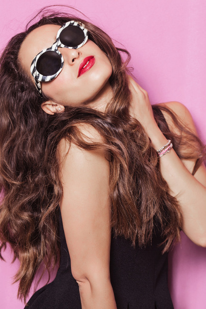 Woman with beautiful hair wearing sunglasses and posing - Fotó, kép