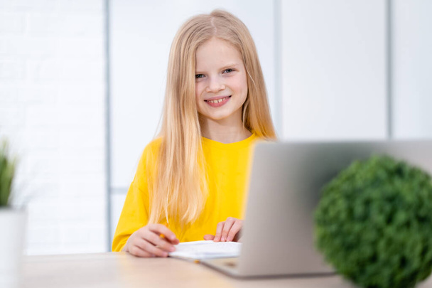 Portrait blonde schoolgirl studying at home doing school homework with laptop. Distance learning online education. Back to school - Foto, Imagem