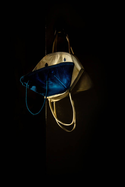 Sommige beschermende maskers opgehangen en verlicht door slechts een lichtstraal en de rest van de scène in het donker. - Foto, afbeelding