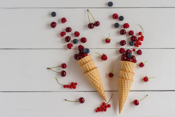 Fresh blueberry, blackberry and raspberry in waffle cone on wooden white background. Top view. - Zdjęcie, obraz