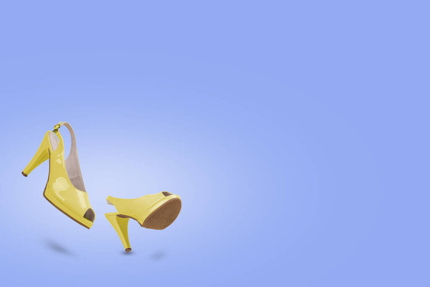 Yellow sandals with high heels in motion on a light purple background. Creative minimal concept of femininity, trend and fashion. Copy space. - Photo, Image