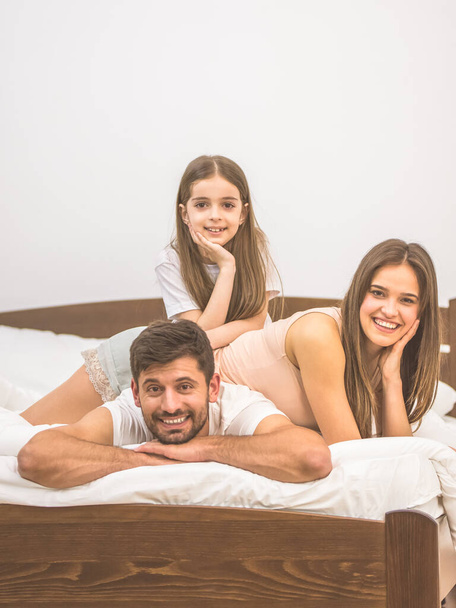 The girl and parents lay on the bed - Foto, Imagen