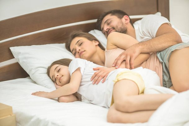 The happy family sleeping on the comfortable bed - Valokuva, kuva