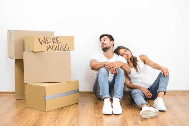 El hombre y la mujer se sientan en el suelo cerca de cajas de cartón - Foto, imagen