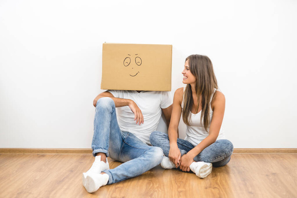 L'homme avec une boîte en carton sur une tête s'assoit près de la femme - Photo, image